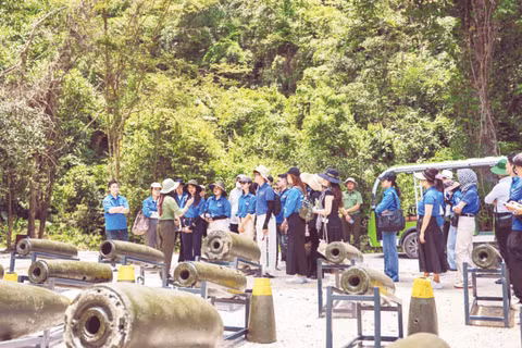 Du khách tham quan khu trưng bày chứng tích bom mìn ngoài trời tại Hang Chỉ Huy.