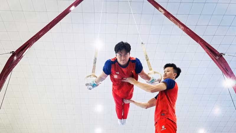 Huấn luyện viên Trương Minh Sang hỗ trợ vận động viên trong bài tập vòng treo.