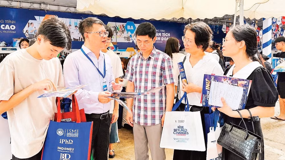 Thí sinh và phụ huynh được giải đáp thông tin tuyển sinh, chương trình đào tạo tại gian tư vấn của Đại học Kinh tế quốc dân. (Ảnh: QUỲNH NGUYỄN)