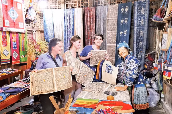 Du khách nước ngoài chọn sản phẩm vải lanh vẽ sáp ong tại Hợp tác xã dệt lanh Lùng Tám.