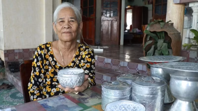 Nghệ nhân Đàng Thị Mỹ Trâm (thôn Bàu Trúc, xã Ninh Phước, tỉnh Khánh Hòa), bên những sản phẩm chạm bạc thủ công truyền thống của đồng bào Chăm. (Ảnh: NGUYỄN TRUNG)