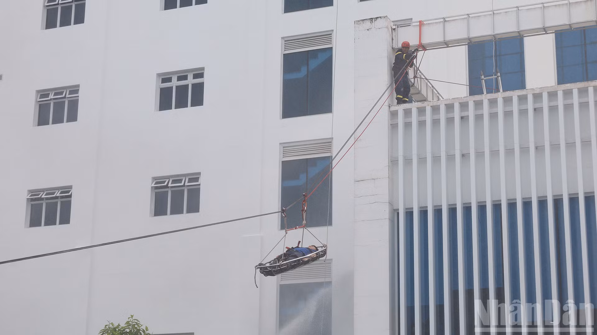 Lực lượng cứu nạn cứu hộ tiếp nhận và đưa người bị nạn xuống đất an toàn trong tình huống giả định xảy ra cháy tại tòa nhà điều hành.