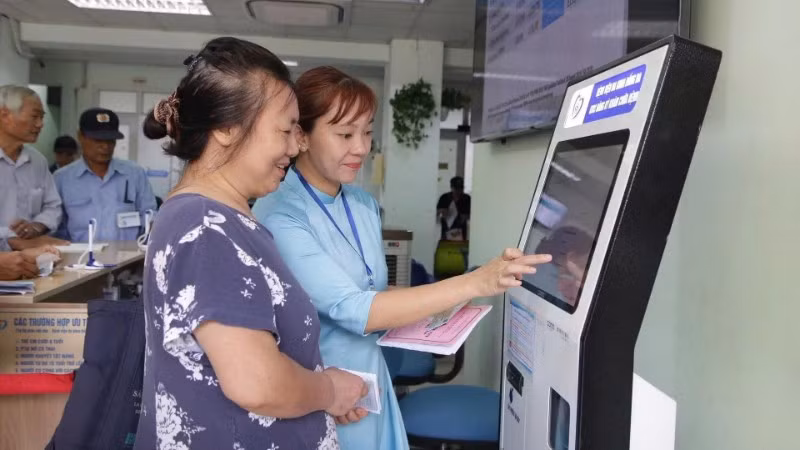 Cán bộ Bệnh viện Đống Đa (Hà Nội) hướng dẫn người dân sử dụng công nghệ số trong việc đăng ký khám, chữa bệnh. (Ảnh HUY HOÀNG)