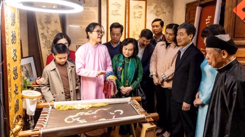 Du khách tìm hiểu nghề thêu tại đình Tú Thị, một điểm đến di sản trong tuyến đình thờ Tổ nghề.