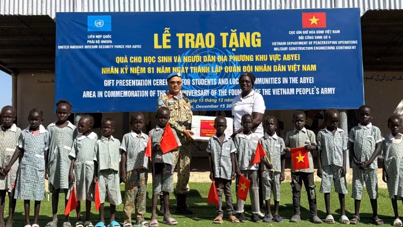 Trung tá Trần Thanh Sơn, Phó Đội trưởng Đội Công binh số 4, trao tặng dụng cụ học tập cho học sinh Abyei. (Ảnh: HẢI YẾN)