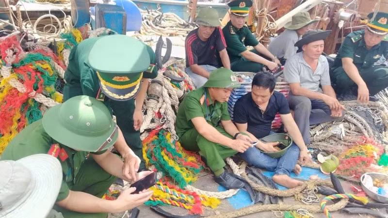 Chiến sĩ Đồn Biên phòng Quỳnh Phương phối hợp với lực lượng công an triển khai “Bình dân học vụ số” cho các thuyền viên trên tàu cá.