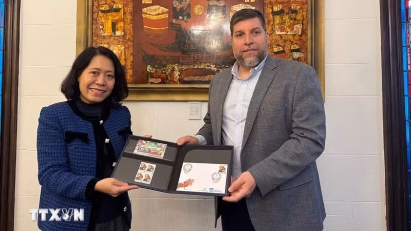 Nghị sĩ Victor Aldaya trao Đại sứ Ngô Minh Nguyệt bộ tem do Bưu chính Uruguay phát hành tháng 12/2013, nhân kỷ niệm 20 năm quan hệ ngoại giao Việt Nam-Uruguay, với chân dung của Đại tướng Võ Nguyên Giáp. (Ảnh TTXVN)