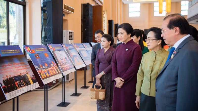 Bà Ngô Phương Ly và bà Naly Sisoulith cùng các khách mời tham quan khu vực Triển lãm ảnh quan hệ Việt Nam-Lào. (Ảnh: Nguyễn Hồng)