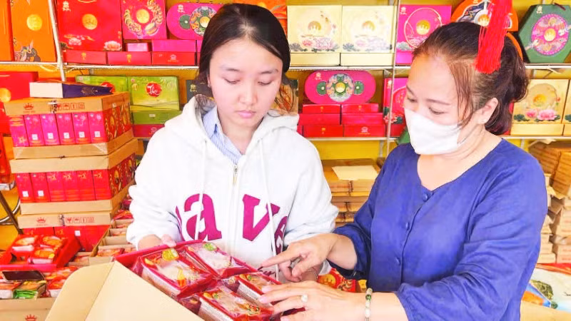 Mẹ con chị Bạch Thị Bích Phượng, chủ một cơ sở bán bánh trung thu trên đường Lê Thánh Tông, phường Buôn Ma Thuột chuẩn bị bánh bán cho khách hàng.