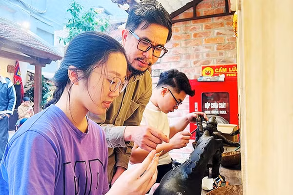 Họa sĩ Nguyễn Tấn Phát hướng dẫn các bạn trẻ thực hành với sơn mài tại đình Hà Vĩ.
