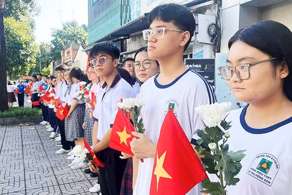 Các em học sinh cầm hoa cúc trắng tiễn biệt các Anh hùng liệt sĩ.