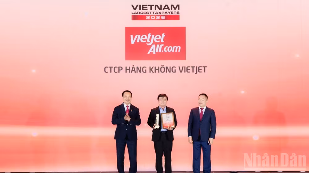 Ông Thái Trọng Cang, Kế toán trưởng Vietjet (đứng giữa) nhận bằng khen và cúp vinh danh doanh nghiệp dẫn đầu nhóm doanh nghiệp hàng không, logistics tư nhân nộp ngân sách lớn nhất Việt Nam năm 2025. (Ảnh: BẢO VY)