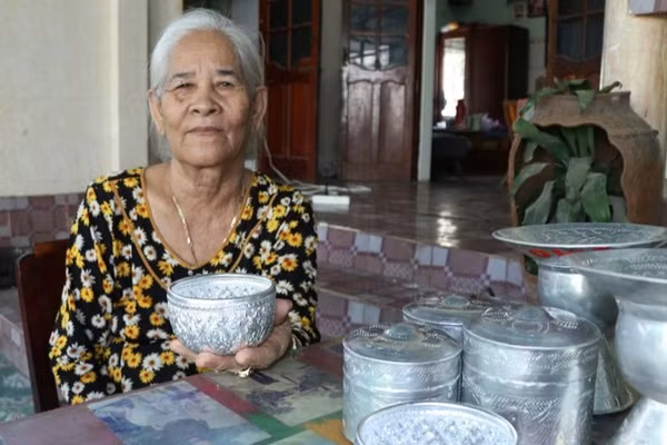 Nghệ nhân Đàng Thị Mỹ Trâm (thôn Bàu Trúc, xã Ninh Phước, tỉnh Khánh Hòa), bên những sản phẩm chạm bạc thủ công truyền thống của đồng bào Chăm. (Ảnh: NGUYỄN TRUNG)
