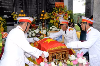 Các cựu chiến binh xã Thông Tân thực hiện nghi thức phủ Quân kỳ cho liệt sĩ Ngô Đức Mai. (Ảnh: THÀNH CHUNG)