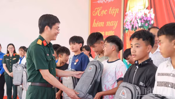 Thiếu tá Trần Văn Hiếu, Giám đốc Chi nhánh Trường Sơn 97 (Binh đoàn 12) trao tặng cặp sách cho học sinh Trường phổ thông nội trú tiểu học và trung học cơ sở Y Tý. (Ảnh: CÔNG HẢI)