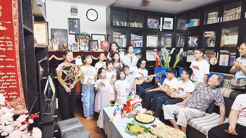 Các em nhỏ hát bài ca "Chiếc đèn ông sao" trong căn phòng của gia đình tác giả.