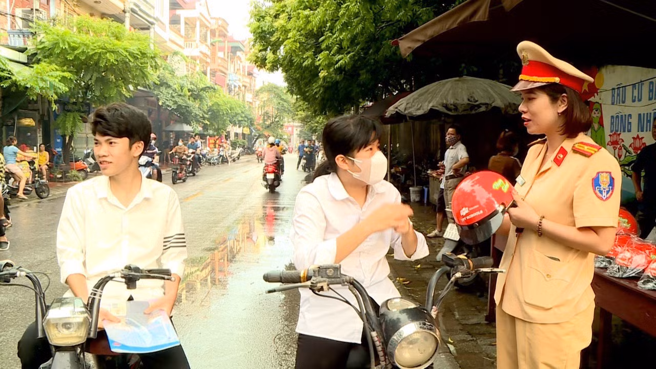 Tổ công tác Phòng Cảnh sát giao thông, Công an tỉnh Bắc Ninh phát miễn phí mũ bảo hiểm cho phụ huynh, học sinh đến điểm thi trên địa bàn.