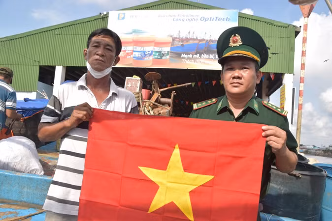 Bộ đội Biên phòng Tiền Giang trao cờ Tổ quốc kết hợp tuyên truyền đánh bắt thủy sản trên biển cho ngư dân.
