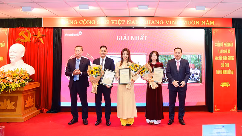 Đồng chí Hồ Xuân Trường - Phó Bí thư Đảng ủy Khối Doanh nghiệp Trung Ương (bên phải) và đồng chí Trần Minh Bình - Ủy viên Ban Chấp hành Đảng bộ Khối Doanh nghiệp Trung Ương, Bí thư Đảng ủy, Chủ tịch Hội đồng quản trị Ngân hàng Công thương Việt Nam (bên trái) trao Giấy chứng nhận và hoa cho các tác giả/nhóm tác giả đạt giải Nhất.