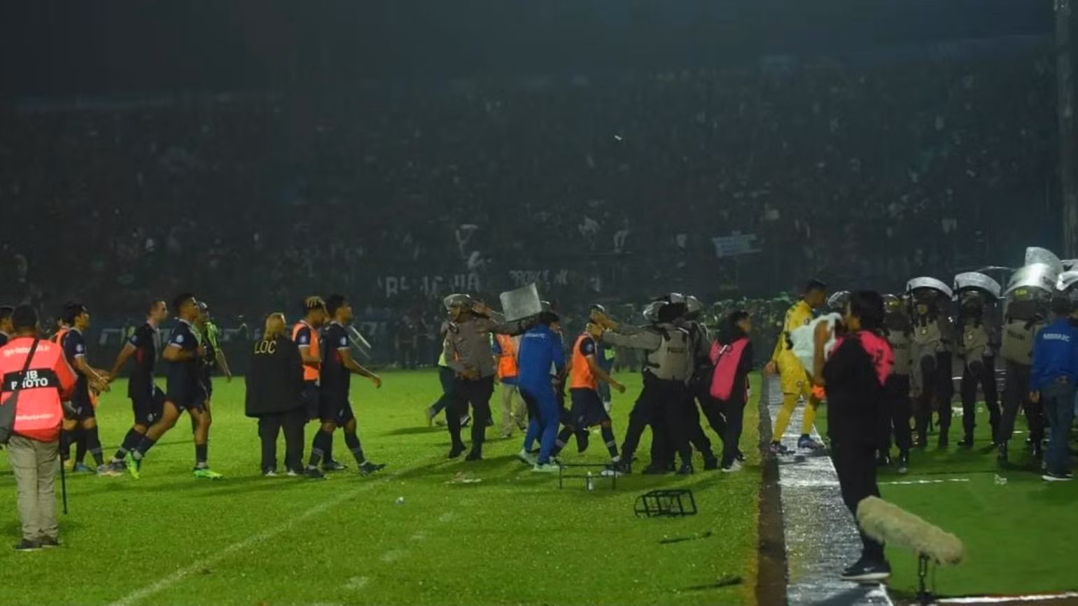 Cầu thủ Arema phải nhờ tới sự bảo vệ của cảnh sát mới có thể rời sân. (Ảnh: Bola.com)
