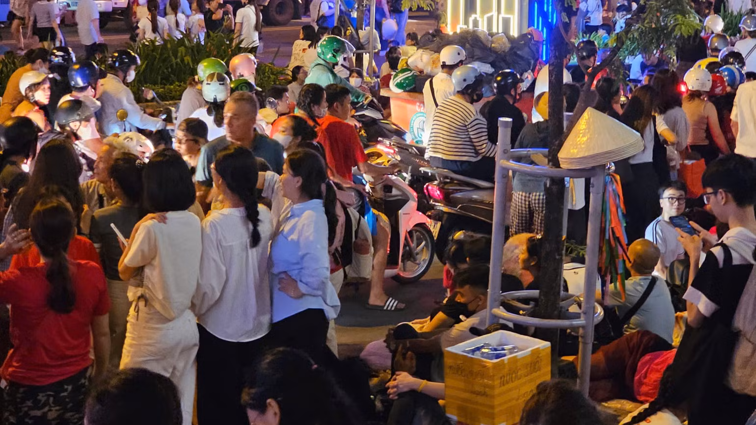 Nhiều người dân đã tập trung dọc vỉa hè. Họ mang theo bạt, đồ dùng cá nhân và thức ăn, sẵn sàng qua đêm để giữ chỗ đến sáng mai. (Ảnh: HẢI AN)