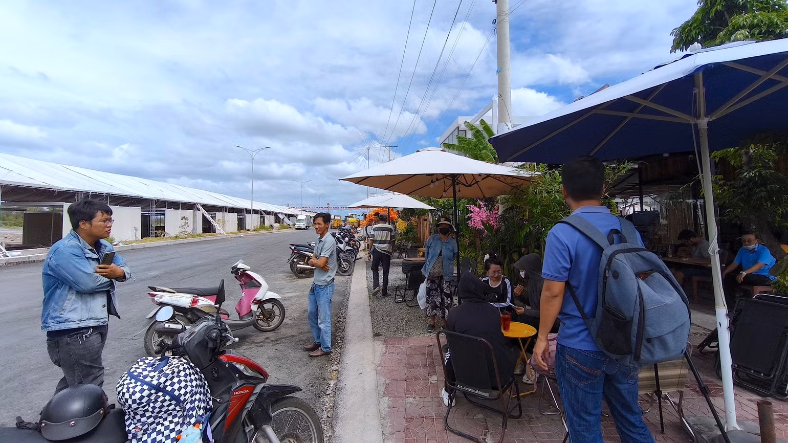 Một nhóm tiểu thương đến từ nhiều tỉnh, thành phố khác nhau tham gia hoạt động hội chợ tại miền biển Sông Đốc tụ tập cà phê “đốt thời gian” vì chưa được đưa hàng vào trong.