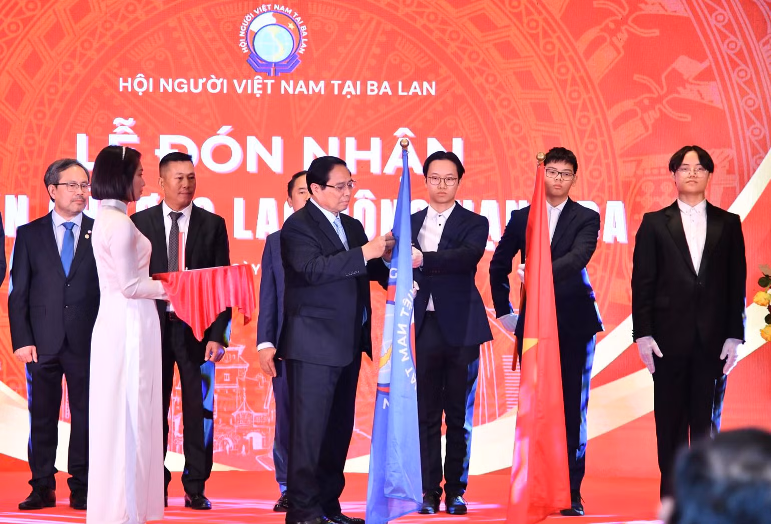 Thủ tướng Phạm Minh Chính gắn Huân chương Lao động hạng Ba lên cờ truyền thống của Hội Người Việt Nam tại Ba Lan (Ảnh: THANH GIANG).