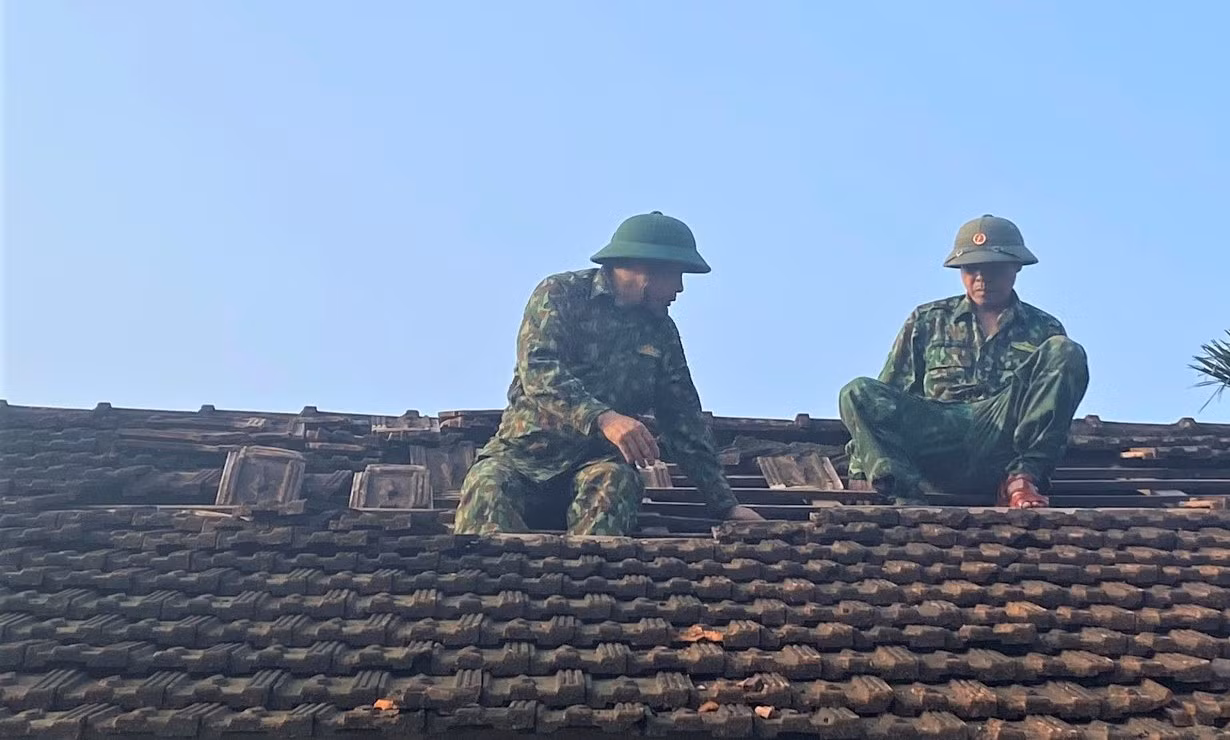 Cán bộ, chiến sĩ Đồn Biên phòng Phúc Sơn giúp người dân lợp lại mái nhà bị hư hỏng.