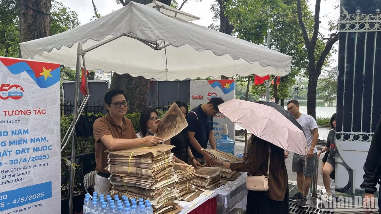 Mặc dù trời mưa to nhưng rất nhiều độc giả đã có mặt từ sớm để được nhận phụ san của Báo Nhân Dân.