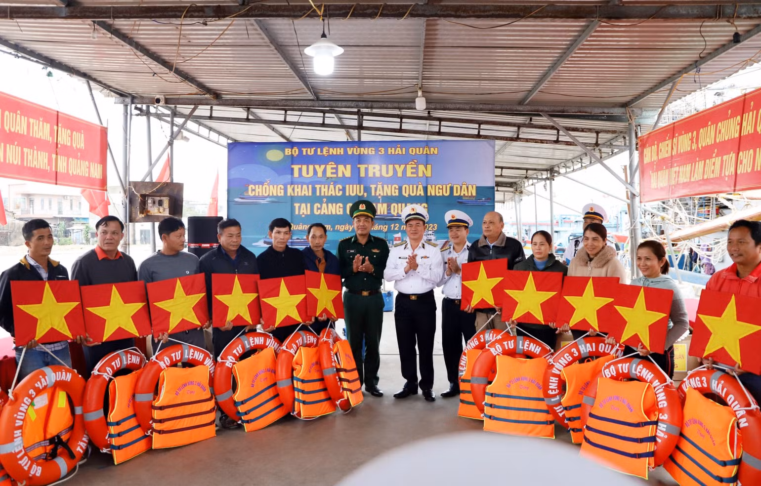 Vùng 3 Hải quân phối hợp với Bộ đội Biên phòng Quảng Nam tặng cờ và áo pháo cho ngư dân tại cảng Tam Quang.