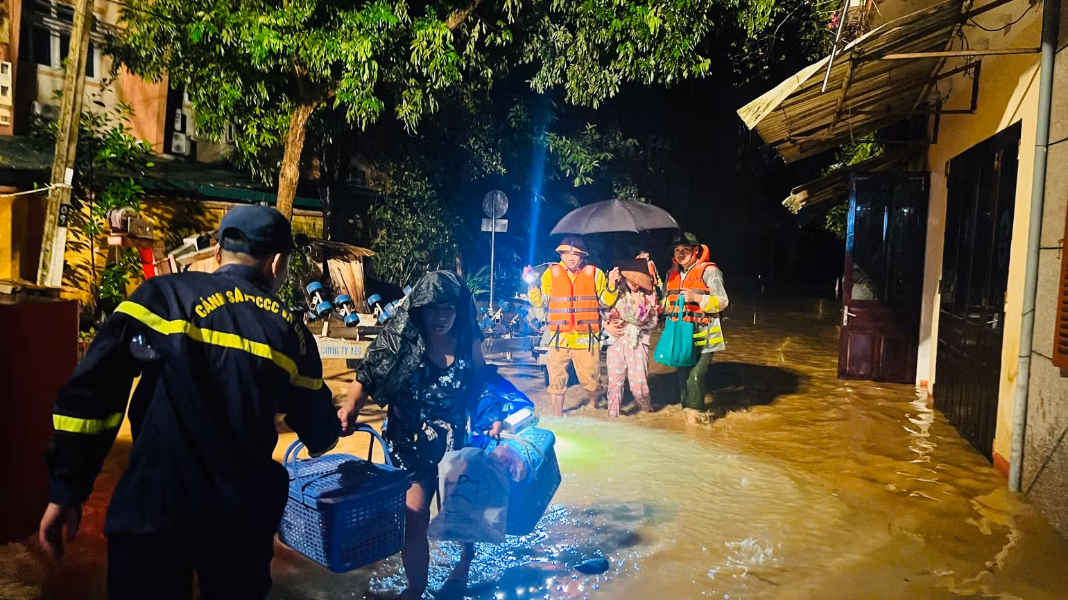 Đưa phụ nữ có con nhỏ ra khỏi vùng nguy hiểm.(Ảnh: THANH SƠN)
