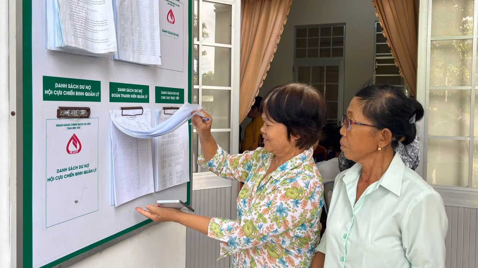 Người dân tìm hiểu thông tin về vay vốn, thủ tục, dư nợ tại điểm giao dịch của Ngân hàng Chính sách xã hội. (Ảnh: HOÀNG TRUNG)