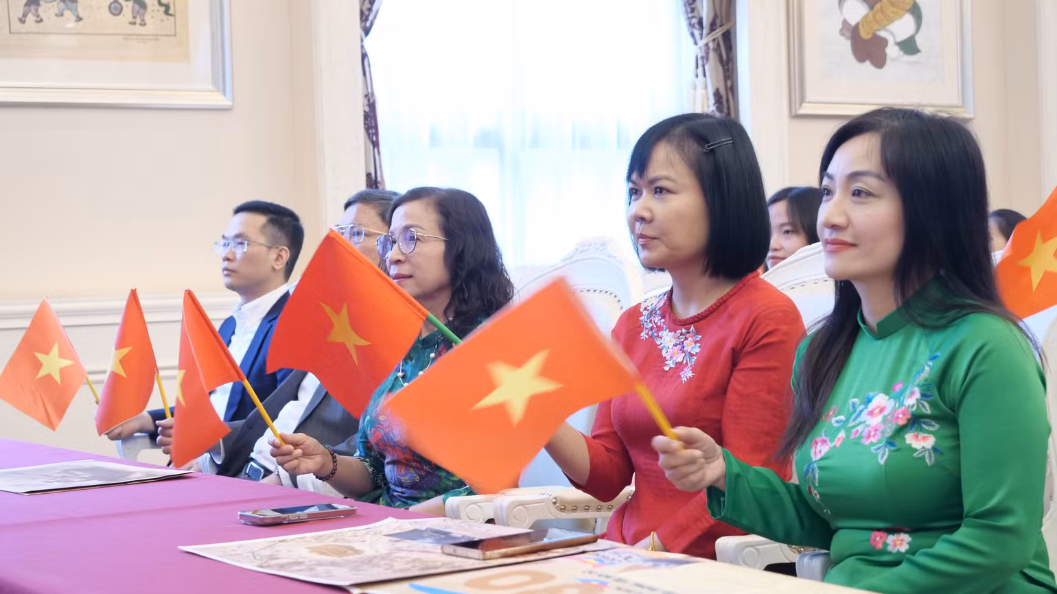 Phu nhân Đại sứ, Hoàng Thị Hương Giang (ngoài cùng bên phải), phu nhân Công sứ, Bùi Thị Hồng Hải (thứ hai từ phải sang) xem cầu truyền hình Lễ diễu binh, diễu hành và Lễ kỷ niệm.