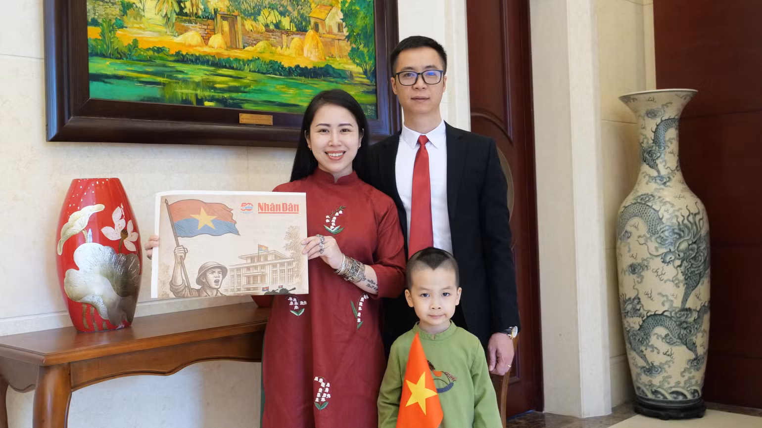 Gia đình anh chị Hoàng Hà-Nhật Linh chụp ảnh với ấn phẩm phụ san đặc biệt Kỷ niệm 50 năm Giải phóng miền nam, thống nhất đất nước của Báo Nhân Dân.