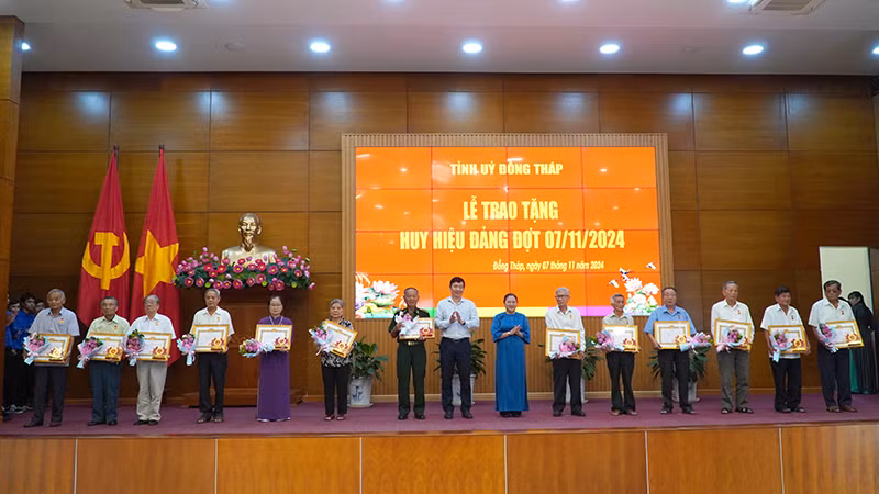 Phó Bí thư Tỉnh ủy, Chủ tịch Ủy ban nhân dân tỉnh Đồng Tháp Phạm Thiện Nghĩa trao Huy hiệu 55 năm tuổi Đảng; Trưởng Ban Tuyên giáo Tỉnh ủy Đồng Tháp Lê Thị Kim Loan tặng hoa chúc mừng các đảng viên. (Ảnh: HỮU NGHĨA)