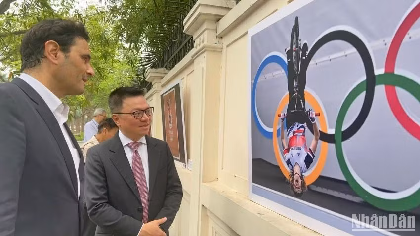 Ông Lê Quốc Minh và các đại biểu tham quan các bức ảnh tại triển lãm.