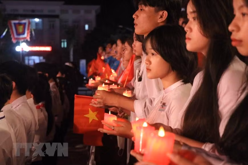 Các em học sinh, sinh viên xúc động thắp nến tri ân các anh hùng liệt sĩ tại điểm cầu tỉnh Bình Định. (Ảnh: TTXVN)