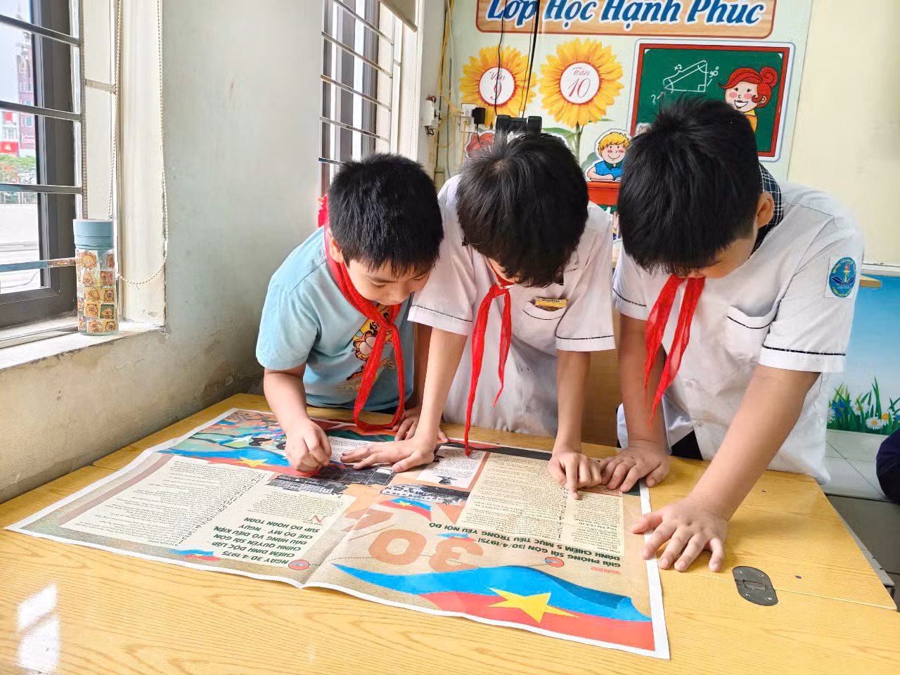 Các bạn nhỏ chăm chú tìm hiểu lịch sử qua những trang Báo in màu đặc sắc.