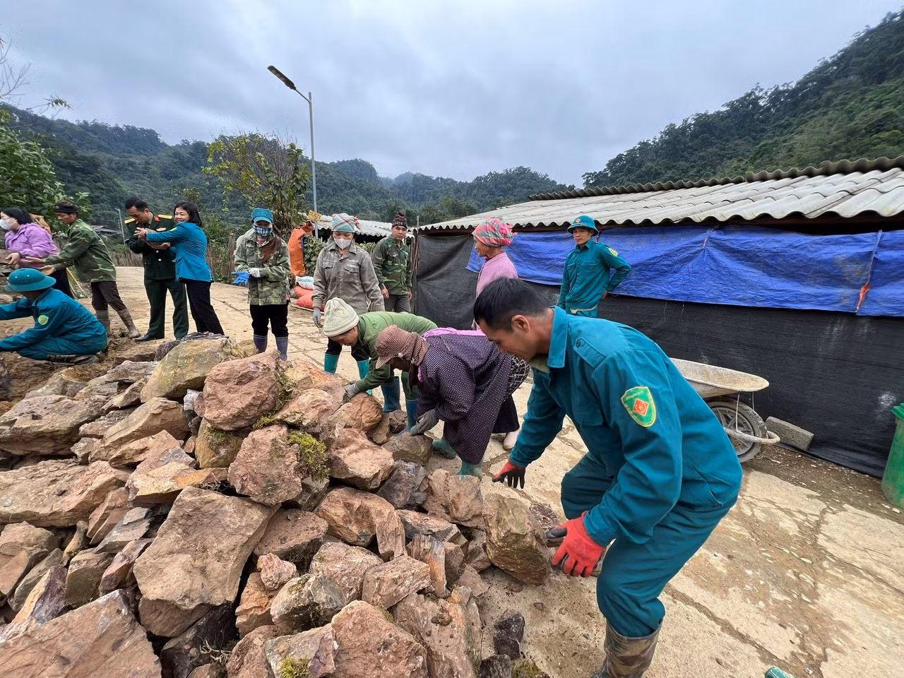Người dân thôn Thôm Khoan chung tay bê từng viên đá xếp hàng rào.