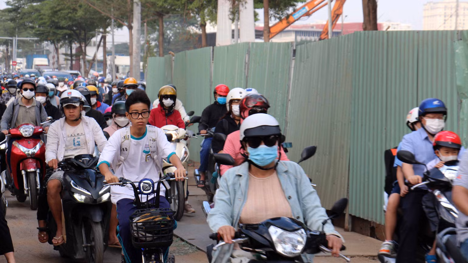 Người dân di chuyển chậm chạp qua đường Nguyễn Văn Linh khu vực công trình dự án hầm chui Nguyễn Văn Linh-Nguyễn Hữu Thọ, quận 7. Phía cần cẩu là hầm chui đang được xây dựng, công trình đang làm rào chắn chiếm nửa đường khiến việc lưu thông qua lại của người dân gặp khó khăn.