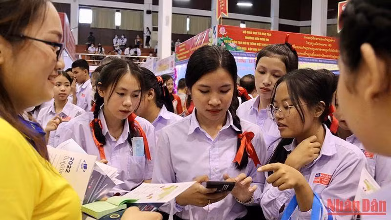 Các em học sinh lớp 12 Lào hào hứng tìm hiểu thông tin về các trường đại học của Việt Nam. (Ảnh: TRỊNH DŨNG)