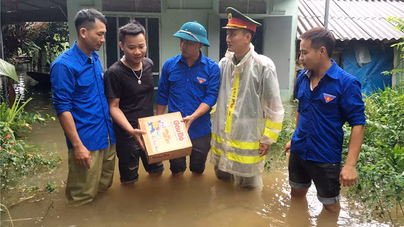 Công an cùng thanh niên tình nguyện cấp phát mỳ tôm cho hộ bị ngập nước.