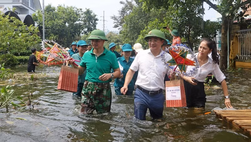 Nghệ sĩ Nhân dân Xuân Bắc cùng Bí thư Thị ủy Trần Anh Tuấn lội nước vào các khu dân cư bị ngập lụt tặng quà cho các cháu thiếu nhi.
