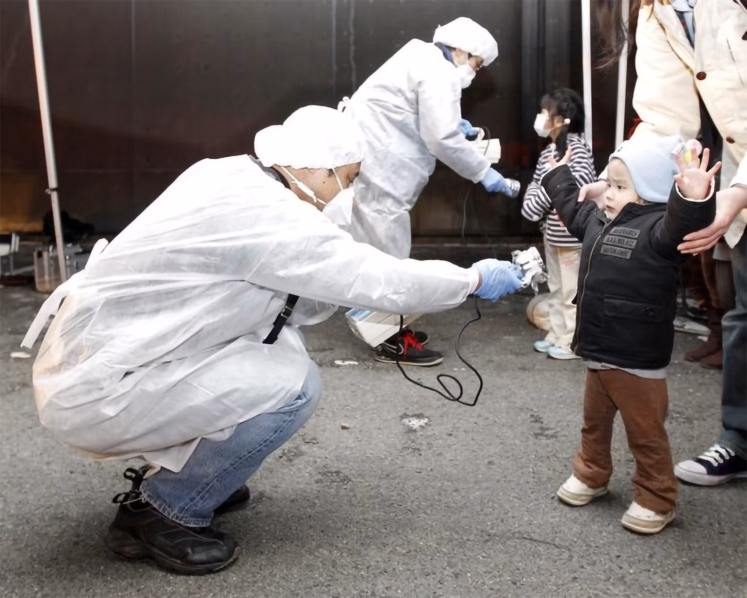 Tại nhà máy điện hạt nhân Fukushima Daiichi ở tỉnh Fukushima, sóng thần đã tràn qua các hệ thống bảo vệ và làm ngập các lò phản ứng, gây ra thảm họa nghiêm trọng. Thảm họa đã làm tê liệt nhà máy điện Fukushima Daiichi, buộc hơn 160.000 cư dân phải sơ tán vì rò rỉ phóng xạ trong không khí. Trong ảnh: Các nhân viên mặc đồ bảo hộ kiểm tra dấu hiệu nhiễm phóng xạ đối với trẻ em đến từ khu vực phải sơ tán gần nhà máy điện hạt nhân Fukushima Daini ở thành phố Koriyama, ngày 13/3/2011. (Ảnh: Reuters) Tại nhà máy điện hạt nhân Fukushima Daiichi ở tỉnh Fukushima, sóng thần đã tràn qua các hệ thống bảo vệ và làm ngập các lò phản ứng, gây ra thảm họa nghiêm trọng. Thảm họa đã làm tê liệt nhà máy điện Fukushima Daiichi, buộc hơn 160.000 cư dân phải sơ tán vì rò rỉ phóng xạ trong không khí. Trong ảnh: Các nhân viên mặc đồ bảo hộ kiểm tra dấu hiệu nhiễm phóng xạ đối với trẻ em đến từ khu vực phải sơ tán gần nhà máy điện hạt nhân Fukushima Daini ở thành phố Koriyama, ngày 13/3/2011. (Ảnh: Reuters)