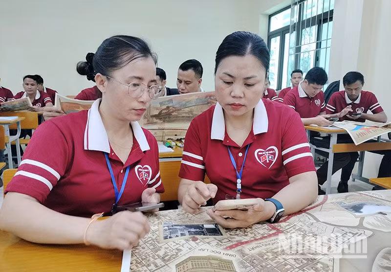 Các cán bộ Lào đang học tập tại Trường cao đẳng Sơn La trải nghiệm công nghệ số bằng điện thoại thông minh bằng cách quét mã QR trên phụ san đặc biệt của Báo Nhân Dân.