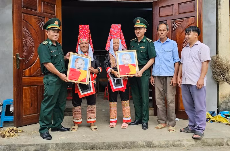 Cán bộ Trạm Biên phòng Cửa khẩu Hoành Mô (Bình Liêu) tặng cờ và ảnh Bác Hồ cho người dân thôn Phai Lầu, xã Hoành Mô.