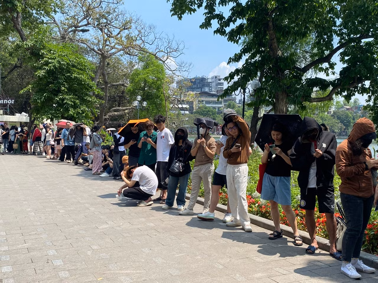 Đến 11 giờ trưa ngày 2/5, dòng người vẫn "đội nắng" xếp hàng để nhận phụ san của Báo Nhân Dân. (Ảnh: ĐỖ THOA)