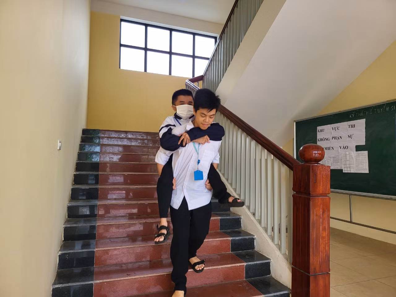 Đầu và cuối giờ đến lớp,các bạn học sinh thay nhau cõng Quang "bàn giao"cho mẹ.