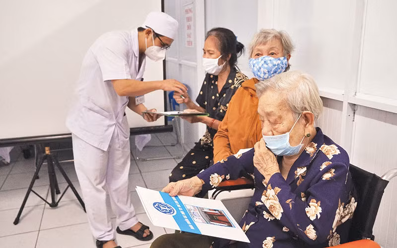 Nhân viên y tế tư vấn, làm thủ tục khám chữa bệnh BHYT cho người cao tuổi.