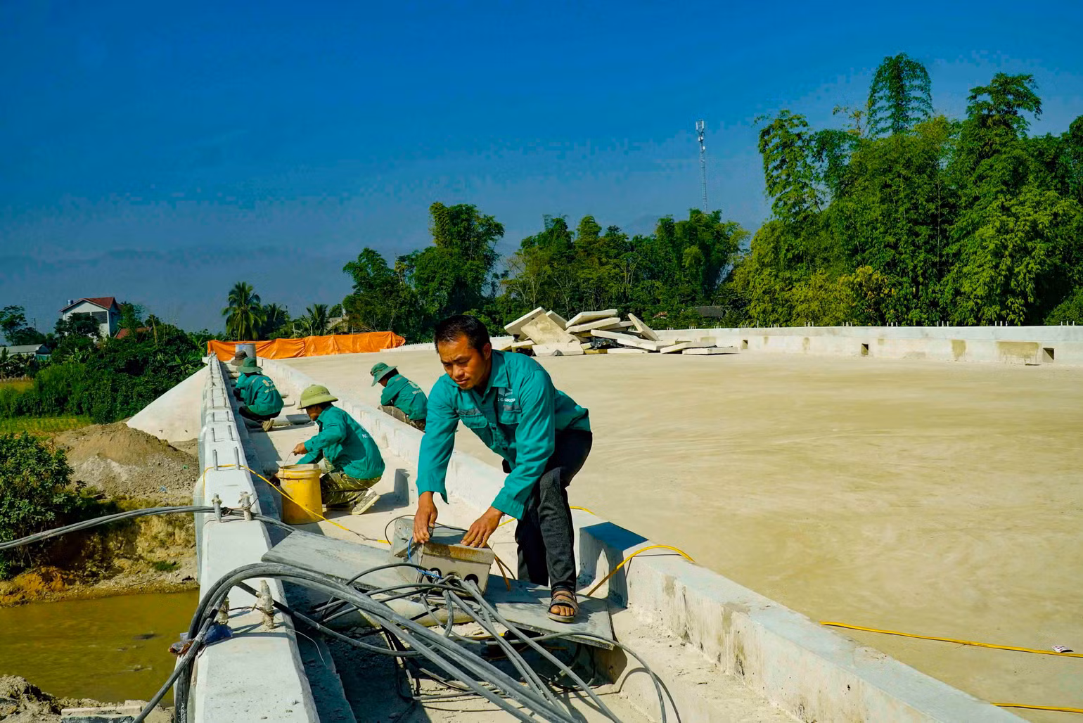 Công nhân Công ty TNHH Xây dựng - Thương mại số 6 tỉnh Điện Biên hoàn thiện các hạng mục cuối trong dự án cầu Pom La bắc qua sông Nậm Rốm.